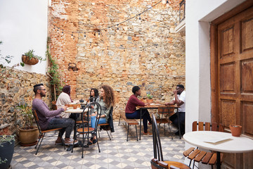 Diverse young people chatting over coffee in a cafe courtyard