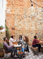 Young people talking over coffee in a cafe courtyard