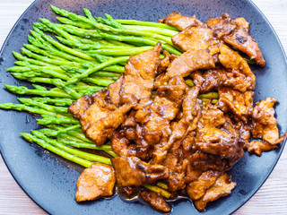 fried Beef with asparagus on black plate close up