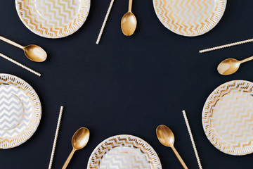 Party decoration background. Golden disposable dishes on dark wooden background