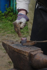 A blacksmith hands forging with a hummer at an open blacksmith festival