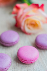 Obraz na płótnie Canvas Tender french dessert macaroons with rose flower on wooden background, soft focus