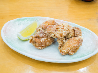 Karaage or Tatsutaage, Japanese fried chicken served with lemon on wooden background