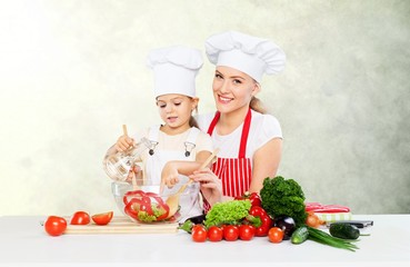 Cute little girl with vegetables in kitchen
