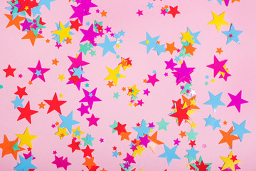 Colorful confetti in shape of stars on pink background