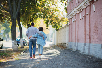 Fototapeta na wymiar Back view of hugging couple walking on street