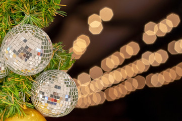 Glass ball ornaments on a Christmas tree and blurred lights.