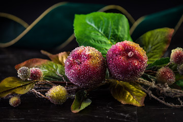 Christmas holiday decoration on black background. sparkly beaded fruit with big green velvet ribbon and bokeh lights. shallow depth of field. 