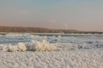 Fototapeta na wymiar Pile of ice floes on the river at the beginning of winter and in the distance can be seen automobile bridge.