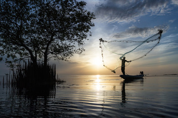 Silhouette of traditional fishermen throwing net fishing at sunrise time, livelihoods of fishermen...