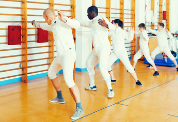 Adult and boys fencers practicing fencing technique