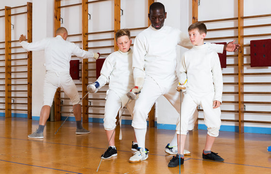 Coach demonstrating fencing movements to kids