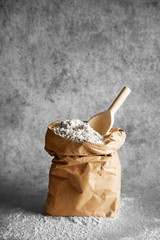 Bag of flour with a wooden spoon isolated on a white background