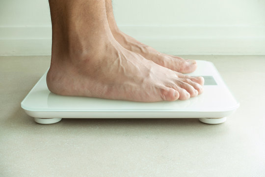 Man's feet on weight checking machine for health care and medical concept background.