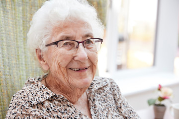 Portrait Of Senior Woman Sitting In Chair In Lounge Of Retirement Home