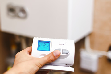 Person near central heating controlling the temperature with a radio device