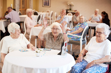 Senior Woman Winning Game Of Bingo In Retirement Home - obrazy, fototapety, plakaty