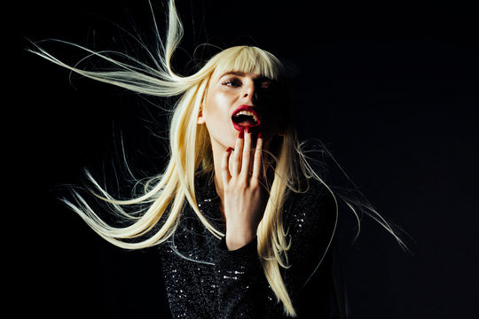 Sensual portrait of a beautiful blonde woman with hair moving in the air, isolated on black studio background