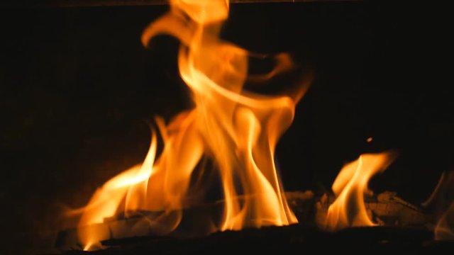 Slow motion yellow and orange flames. Closeup of log burning in woodstove.