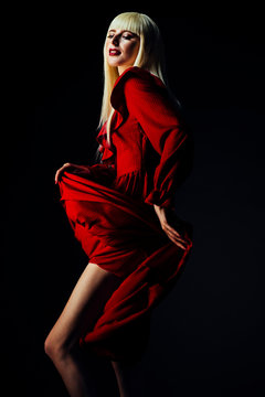 Portrait of blonde woman in  red dancing, isolated on black