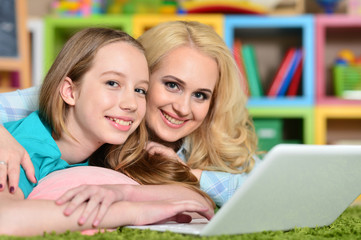 Fototapeta na wymiar Portrait of young woman with girl using laptop