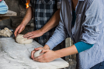 Woman and man shaping dough for bread