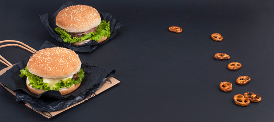 Two hamburger on a black background for lunch. Fast food and snacks. Free space for text. Copy space. Flat lay. Banner.
