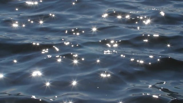 Slow motion blue lake water with brilliant sparkles from sun. 