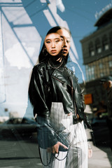 Street stylish portrait of a girl of Asian appearance on the streets of the city with double exposure on a sunny day fashionable clothes