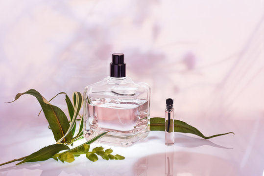 Different perfume bottles and sampler on a pink floral background. Selective focus. Perfumery collection, cosmetics