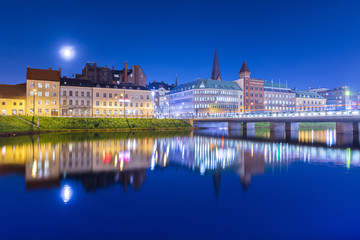 Night city mirrored in the water. Evening panorama of an old European town. Cityscape of Malmo, Sweden