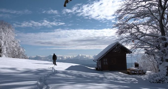 Man walking in snow, with mountins in front of him.