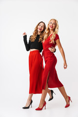 Happy young two girls friends posing isolated over white wall dressed in black and red clothes.