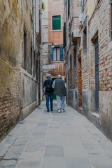 Fototapeta na wymiar Alley in old town. Older couple (Venice - Italy)