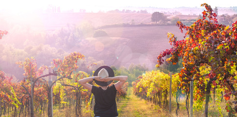 Girl in a hat at sunset. Nature Italy, hills and grape fields in the sunlight. Glare and sun rays...