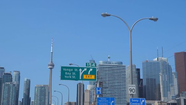 Slomo driving approaching Toronto. Passing signs for Yonge and Bay streets. Driving on Gardiner Expressway, Toronto, Ontario, Canada.