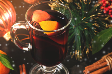 Hot winter Christmas drink mulled wine in a glass mug in a cozy sunlight. Selective focus.