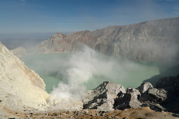 Crater with acidic crater lake, Kawah Ijen the famous tourist attraction, where sulfur is mined. Extraction of sulfur in the crater of a volcano. Sulfur gas, smoke.