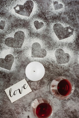 Valentines day. Two glasses of wine red, candle and heart of flour on gray background. Top view