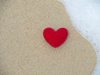 Picture of red heart on the beach sand.