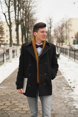 young hipster man with laptop in hand with a urban look in city. in the city winter