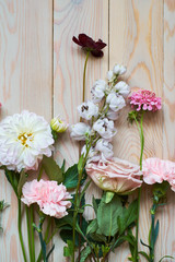 young flowers on rustic wooden boards background flat lay top view