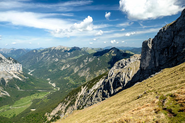 Alpental mit weißen Wolken und Felsen