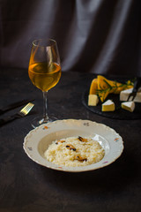 risotto with mussels (seafood rice) in a white plate and a glass of white wine on a dark background