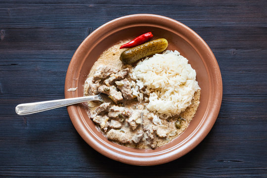 eating of Beef Stroganoff dish from brown plate