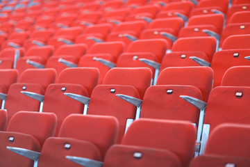 Rows of red numbered seats with armrests in a large auditorium