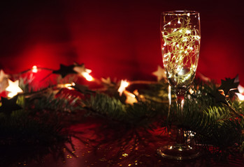 Wineglass with christmas garland on red background.
