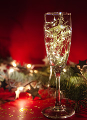 Wineglass with christmas garland on red background.
