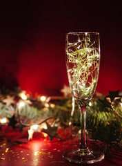 Wineglass with christmas garland on red background.
