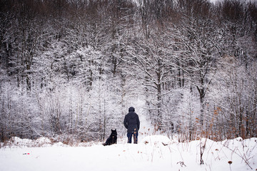 Man walking with his dog in winter forest
